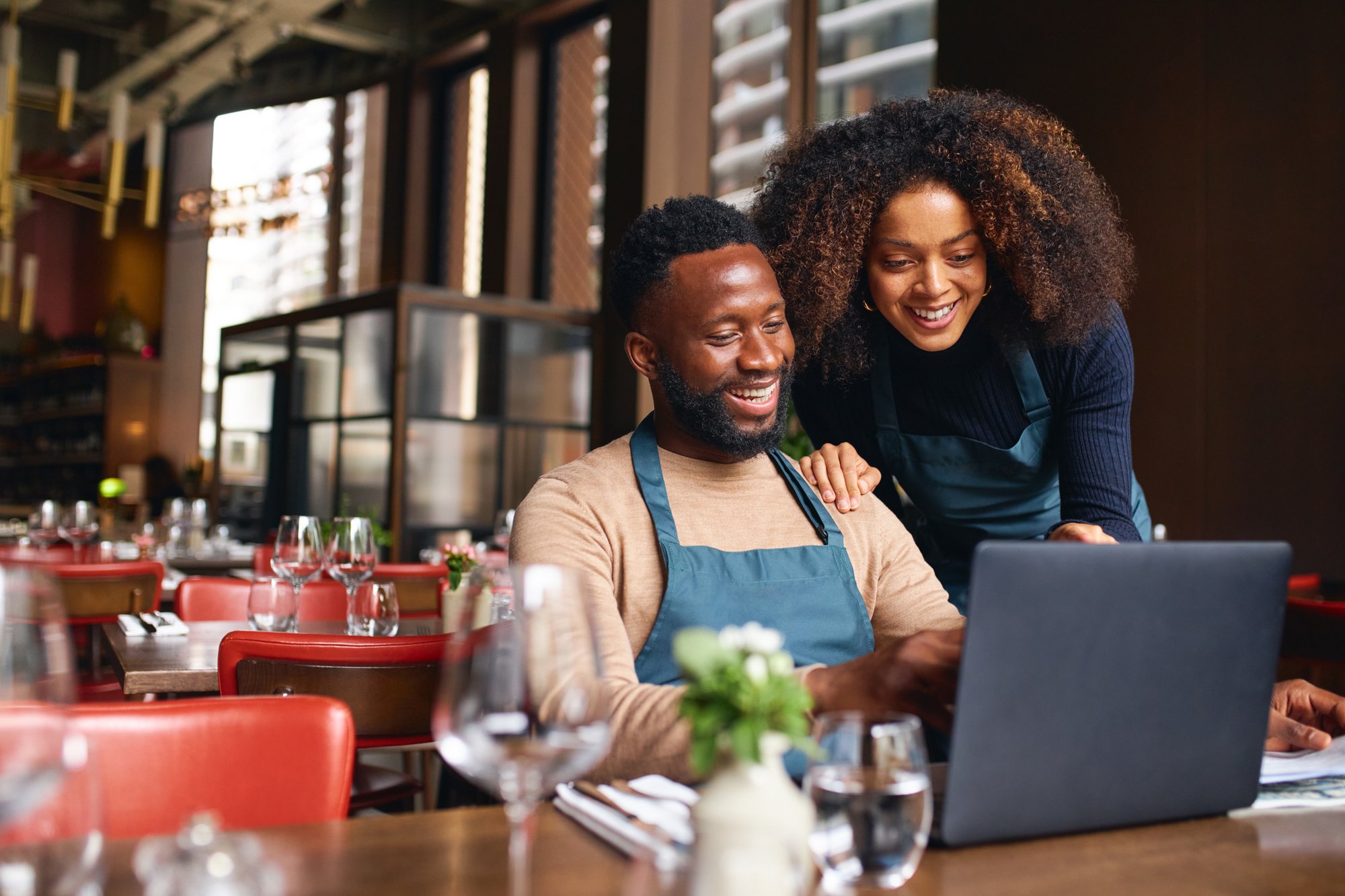 Small business owners using laptop in restaurant Small business owners using laptop in restaurant